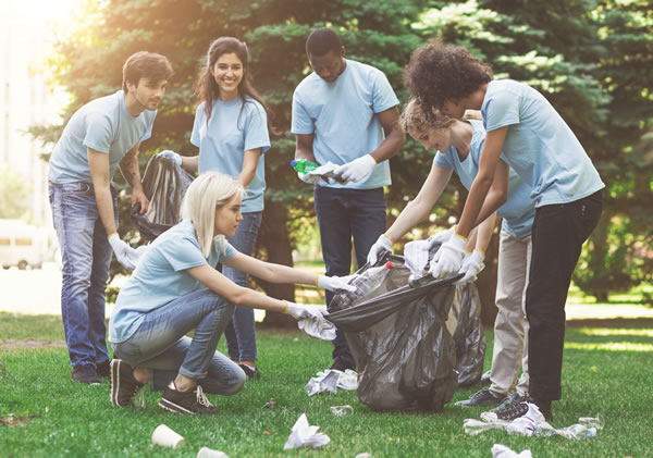Young people volunteering (picking up trash in a park)